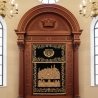 Magnificent hand-carved wooden Aron Kodesh with embroidered curtain, epitomizing premium synagogue furniture manufacturing.