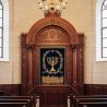 Aron Kodesh: Ornate hardwood craftsmanship with blue velvet and gold embroidery.