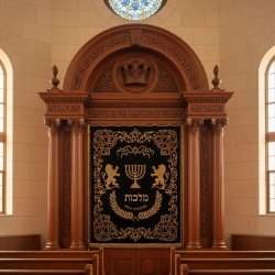 Majestic hand-carved Aron Kodesh with gold-embroidered velvet parochet, a masterpiece of synagogue furniture craftsmanship.