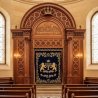 Stunning Aron Kodesh with exquisite wood carvings and blue velvet Parochet, embodying premium synagogue furniture manufacturing.